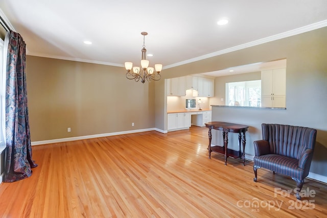 living area featuring ornamental molding, a notable chandelier, and light wood-type flooring