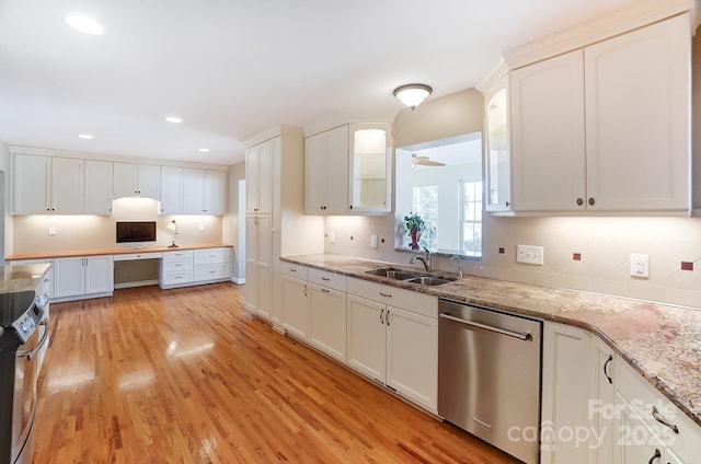 kitchen with sink, dishwasher, light stone countertops, white cabinets, and light wood-type flooring