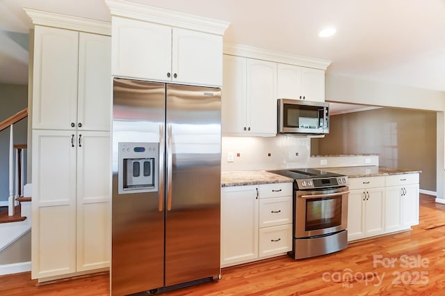 kitchen featuring appliances with stainless steel finishes, light stone countertops, light hardwood / wood-style flooring, and white cabinets