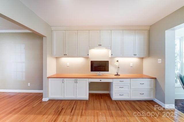 kitchen featuring white cabinetry, wood counters, built in desk, and light hardwood / wood-style floors