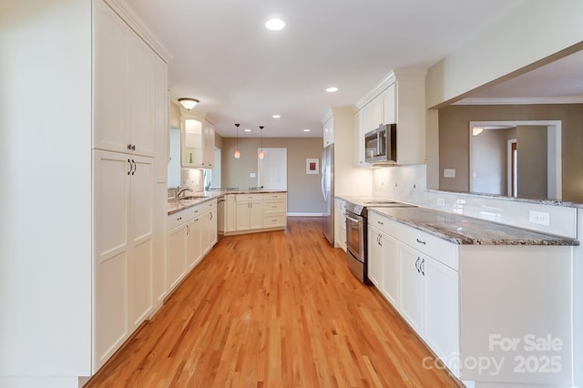 kitchen featuring white cabinetry, decorative light fixtures, stainless steel appliances, and kitchen peninsula