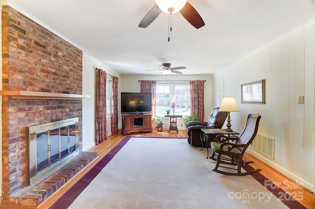 living room featuring a brick fireplace and light wood-type flooring