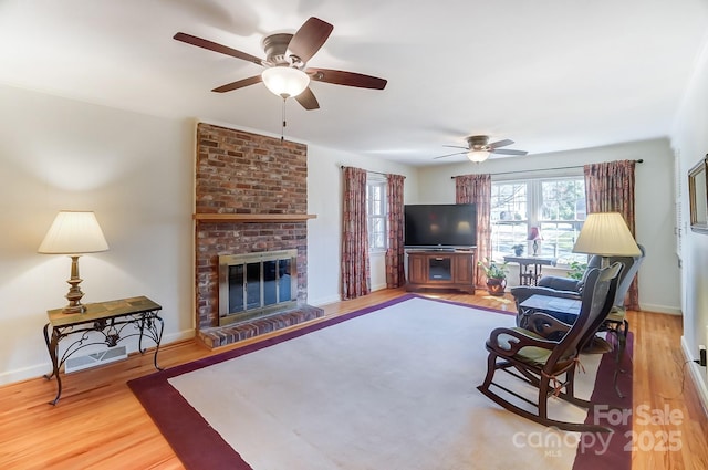 living room featuring hardwood / wood-style flooring, ceiling fan, and a fireplace