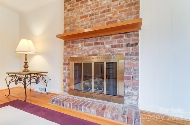 interior details with wood-type flooring and a brick fireplace