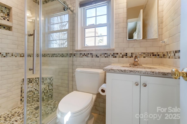 bathroom featuring vanity, a shower with shower door, tile walls, and toilet