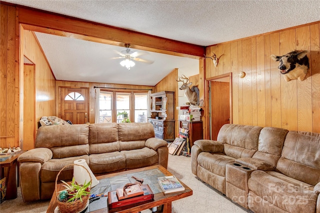 living room with light carpet, a textured ceiling, ceiling fan, beam ceiling, and wood walls