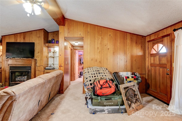 carpeted living room featuring ceiling fan, wood walls, ornamental molding, and a textured ceiling