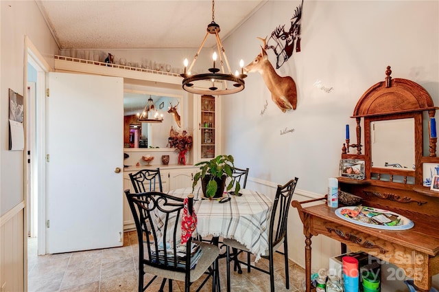 dining area featuring crown molding, lofted ceiling, a textured ceiling, and a chandelier