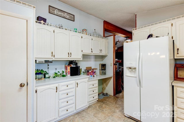 kitchen featuring white cabinets, a textured ceiling, and white fridge with ice dispenser