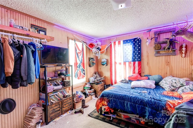 bedroom featuring wood walls, carpet floors, and a textured ceiling