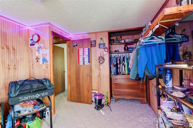 bedroom with light carpet, a textured ceiling, and wood walls