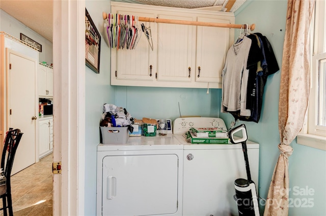 washroom with cabinets, light tile patterned floors, a textured ceiling, and washing machine and clothes dryer