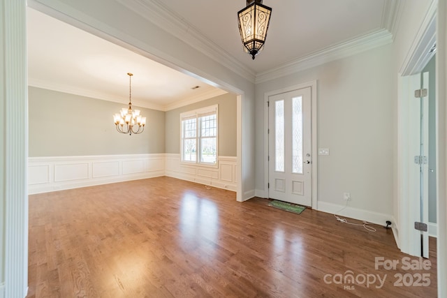 entryway with a chandelier, crown molding, and hardwood / wood-style flooring