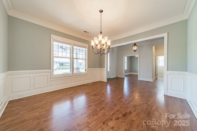 empty room with dark wood-type flooring, crown molding, and a chandelier