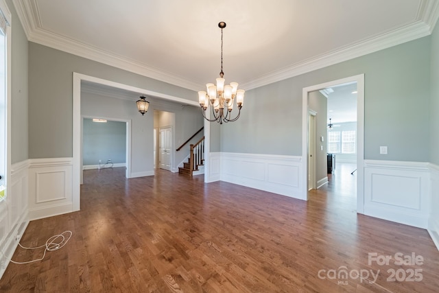 empty room featuring ceiling fan with notable chandelier, dark hardwood / wood-style flooring, and crown molding