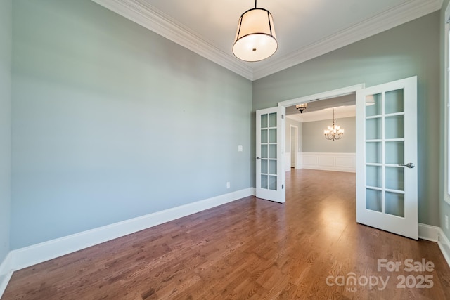 spare room with a chandelier, french doors, ornamental molding, and hardwood / wood-style flooring