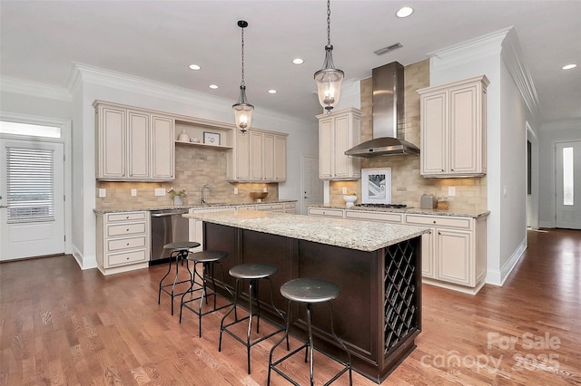 kitchen with appliances with stainless steel finishes, a center island, wall chimney exhaust hood, decorative backsplash, and a breakfast bar area