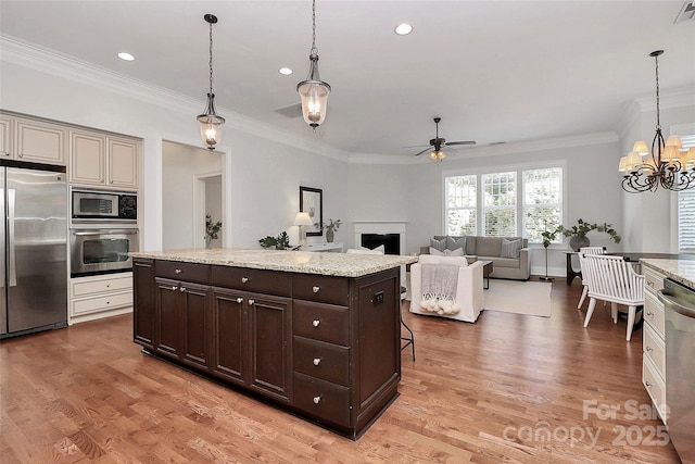 kitchen featuring decorative light fixtures, dark brown cabinetry, appliances with stainless steel finishes, and ceiling fan with notable chandelier