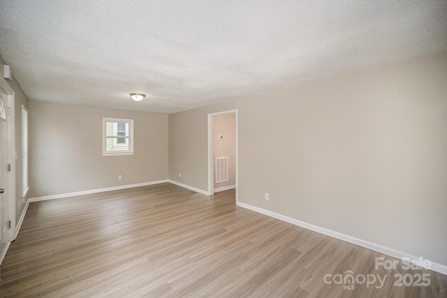 spare room with a textured ceiling and light hardwood / wood-style floors