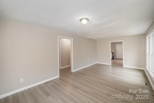 spare room with light hardwood / wood-style floors and a textured ceiling