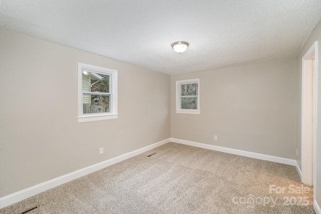 carpeted empty room with a textured ceiling