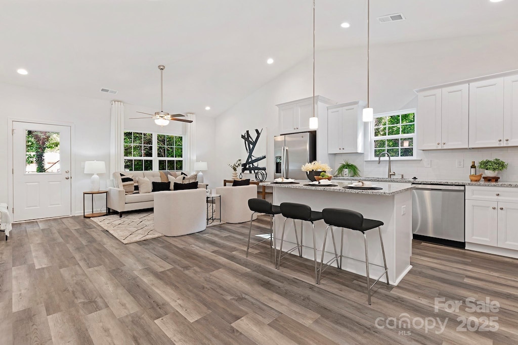 kitchen featuring light stone counters, stainless steel appliances, ceiling fan, decorative light fixtures, and white cabinetry