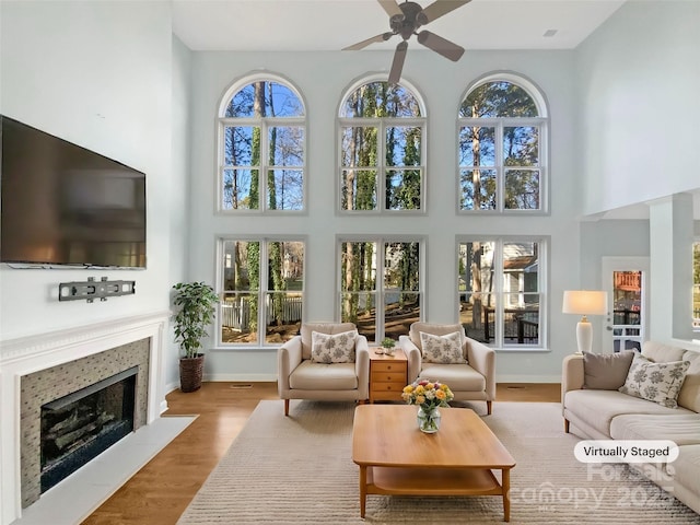 living room featuring ceiling fan, light hardwood / wood-style floors, and a towering ceiling