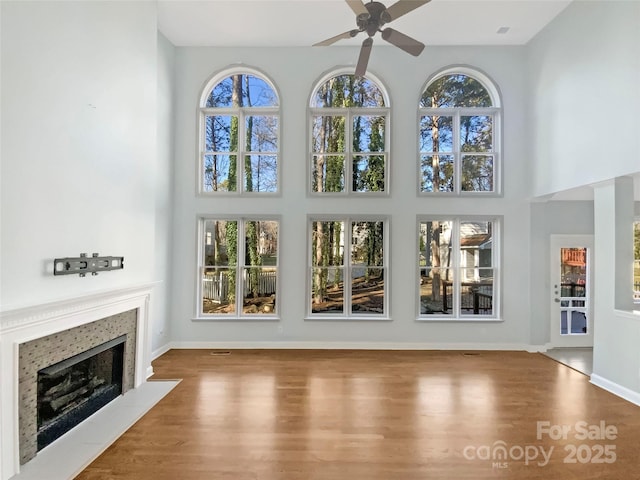 unfurnished living room featuring ceiling fan, wood-type flooring, and a high ceiling