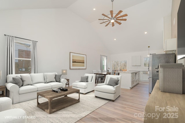 living room featuring ceiling fan, light hardwood / wood-style floors, and high vaulted ceiling