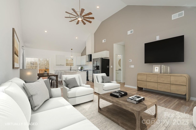 living room with high vaulted ceiling, sink, ceiling fan, and light hardwood / wood-style flooring