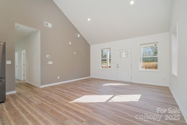 unfurnished living room featuring high vaulted ceiling and light wood-type flooring