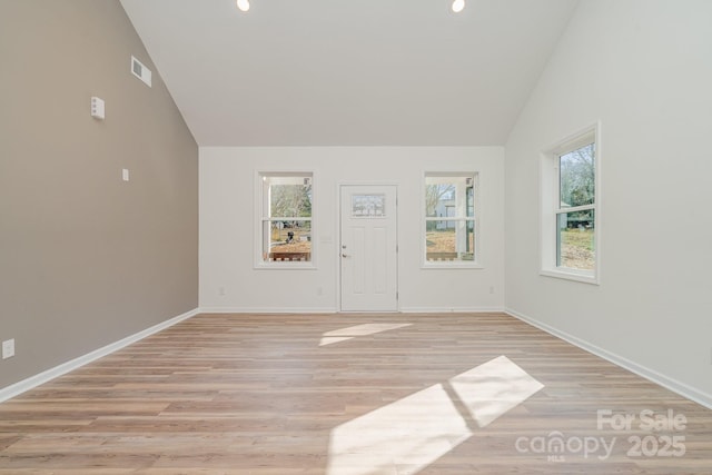 spare room with high vaulted ceiling and light wood-type flooring