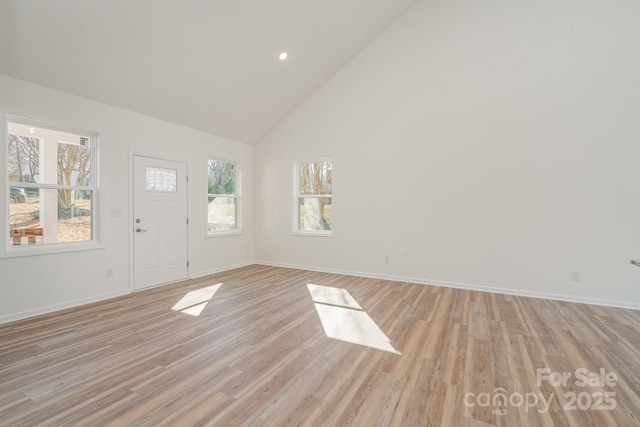 foyer entrance with high vaulted ceiling and light wood-type flooring