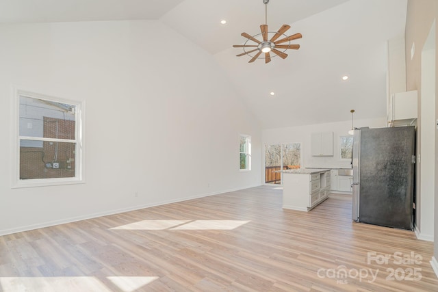 unfurnished living room featuring high vaulted ceiling, ceiling fan, and light wood-type flooring