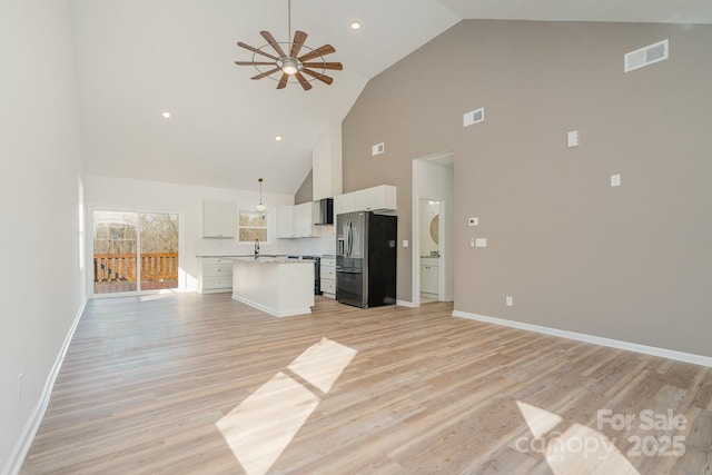 unfurnished living room with sink, light hardwood / wood-style flooring, high vaulted ceiling, and ceiling fan