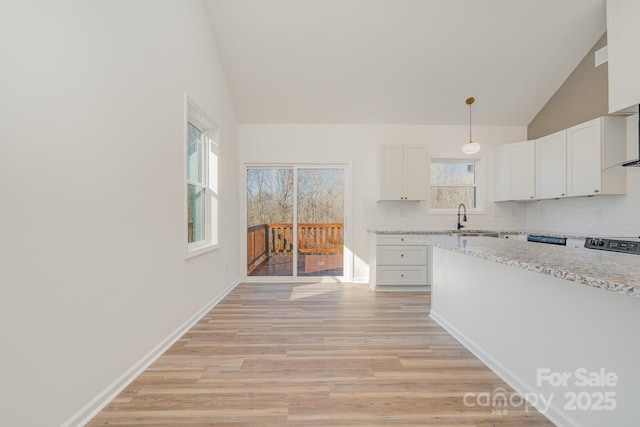 kitchen with hanging light fixtures, light stone countertops, sink, and white cabinets