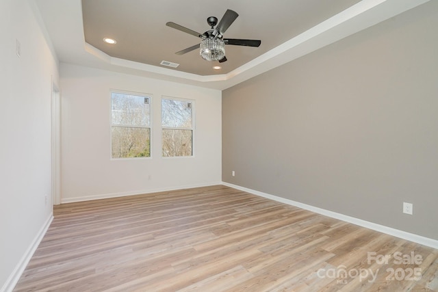 unfurnished room featuring ceiling fan, a raised ceiling, and light hardwood / wood-style flooring