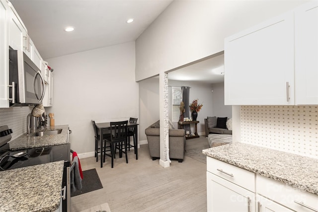 kitchen with light stone counters, white cabinets, appliances with stainless steel finishes, and sink