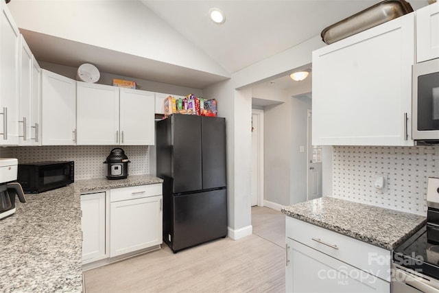 kitchen with black appliances, tasteful backsplash, white cabinetry, and lofted ceiling