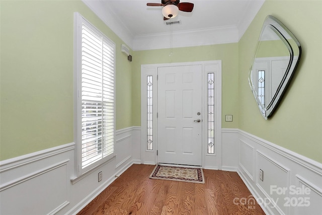 foyer with light hardwood / wood-style floors, ornamental molding, and ceiling fan