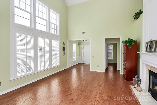 unfurnished living room featuring dark hardwood / wood-style floors, a high end fireplace, and a towering ceiling