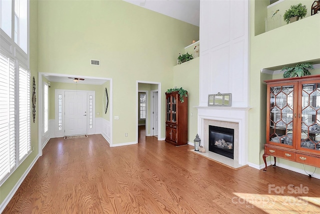 living room featuring a healthy amount of sunlight, a towering ceiling, and hardwood / wood-style floors