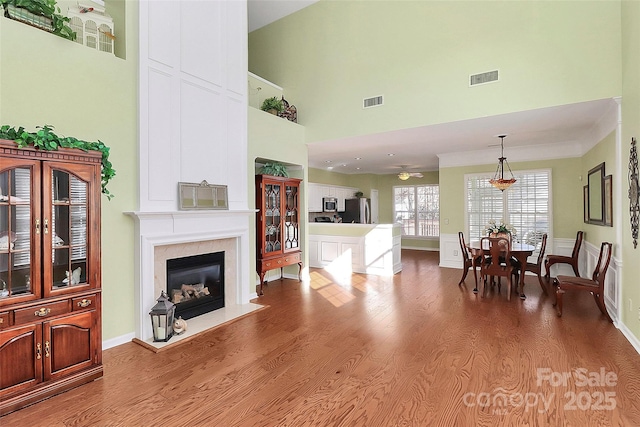 living room with ceiling fan, hardwood / wood-style flooring, and a towering ceiling