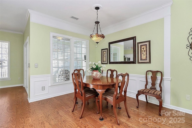 dining space featuring a healthy amount of sunlight, ornamental molding, and light hardwood / wood-style floors