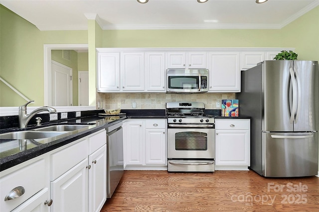 kitchen featuring white cabinets, backsplash, appliances with stainless steel finishes, and sink