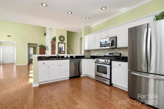 kitchen with white cabinetry, stainless steel appliances, kitchen peninsula, and sink