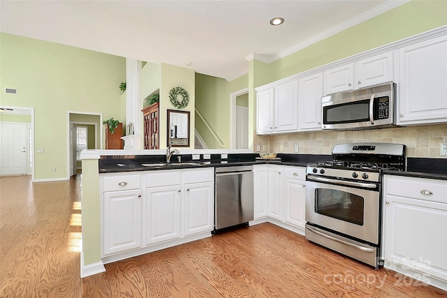 kitchen featuring kitchen peninsula, stainless steel appliances, and white cabinetry