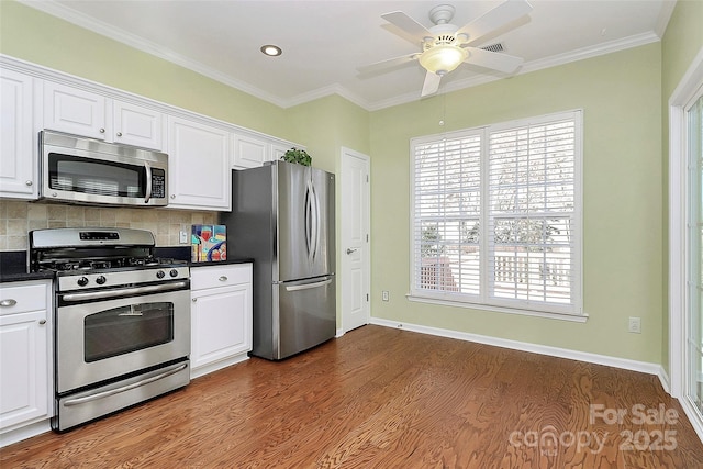 kitchen featuring decorative backsplash, white cabinets, appliances with stainless steel finishes, and ornamental molding