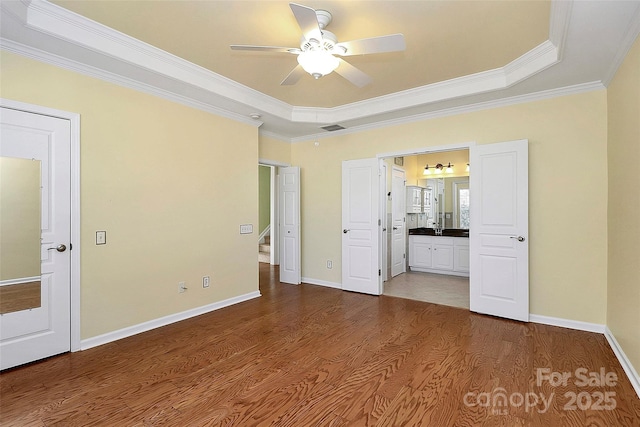 unfurnished bedroom featuring hardwood / wood-style floors, ornamental molding, and a raised ceiling