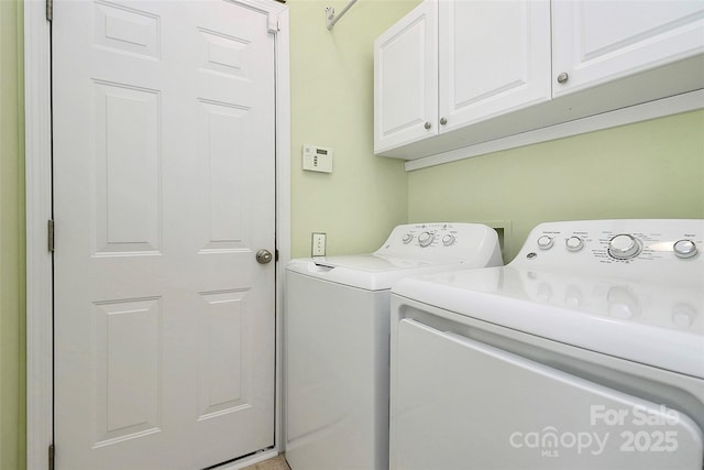 clothes washing area with washing machine and dryer and cabinets